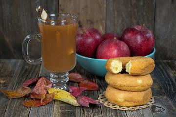 apple cider with donut stack and red apples in turquoise bowl on rustic wood