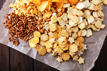 Salty snacks. Pretzels, chips, crackers on brown wooden backgroun d