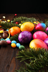 Chocolate Easter eggs, colorful eggs and sweets on wooden background