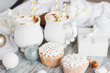 Obraz na płótnie Canvas Cups with cacao and marshmallow, cupcakes and different Christmas decorations, wooden background