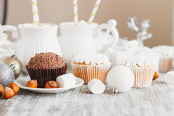 Cups with cacao and marshmallow, cupcakes and different Christmas decorations, wooden background