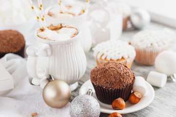 Cups with cacao and marshmallow, cupcakes and different Christmas decorations, wooden background