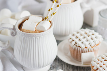 Cups with cacao and marshmallow, cupcakes and different decorations