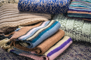 Fototapeta premium Warm woolen sweaters and a scarf knitted on knitting needles.
