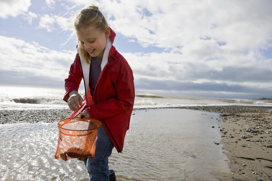 Young girl looking into fishnet at beach