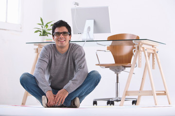 Obraz na płótnie Canvas Man sitting on the floor smiling in an office