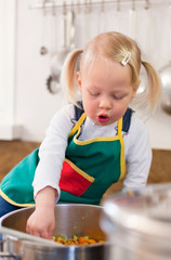 Toddler girl cooking in kitchen