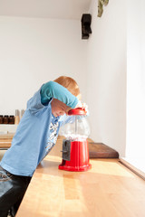 Boy opening gum ball machine in kitchen