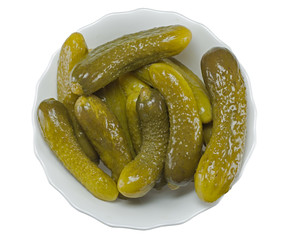some pickled cucumbers in a glass bowl on a white