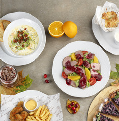 dining table with dishes: soup, salad, meat, French fries with sauce
