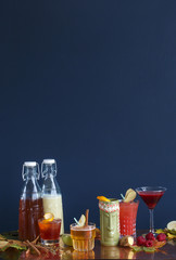 Alcoholic cocktails in glasses on the table, milk and juice in bottles for cocktails with fruits and berries