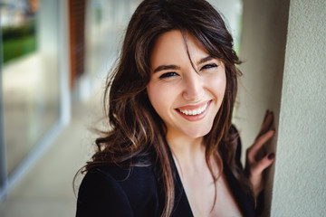 Portrait of a beautiful brunette laughing by the wall