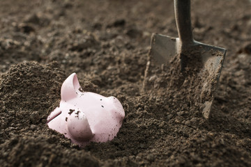 Shovel digging up piggy bank