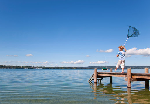 Boy Fishing With Net In Lake