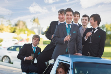 Teenage boys in suits smiling from car © Image Source RF