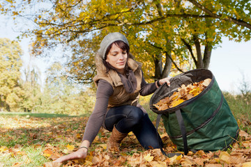 Woman gathering fall leaves in park