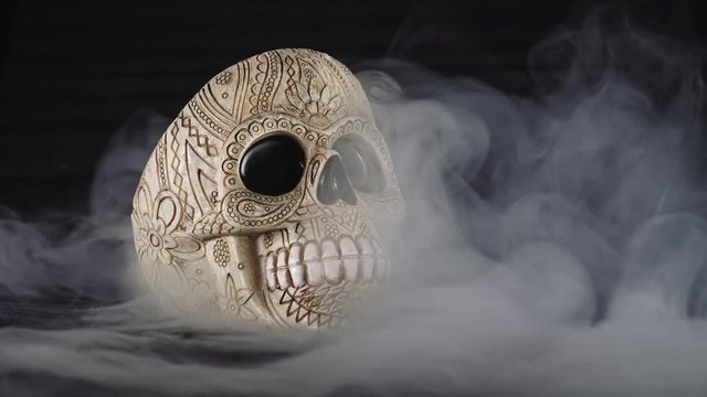 Skull covered in smoke on a dark background.
