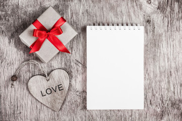 Notepad with blank page, gift box and wooden heart. Copy space. Valentine's Day. Monochrome