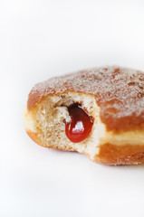German fried donut, so called Krapfen, Berliner or Pfannkuchen, filled with rose hip jam and dusted with cinnamon sugar, traditionally eaten at carnival and at New Year's Eve on white background