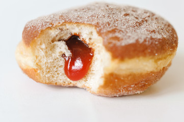 German fried donut, so called Krapfen, Berliner or Pfannkuchen, filled with rose hip jam and dusted with cinnamon sugar, traditionally eaten at carnival and at New Year's Eve on white background - obrazy, fototapety, plakaty