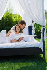 Couple having breakfast on bed in garden