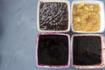 Four different types of jam on a gray background.
