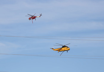 Fototapeta na wymiar Red and Yellow Fire Helicopters Pass Each Other in Fire Fight