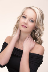 Fototapeta premium Beautiful blond woman in curly hair and black top on light background