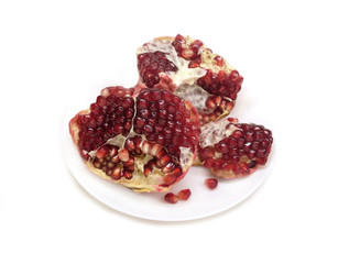 Separated pomegranate with ripe seeds on a plate isolated on white background top view closeup