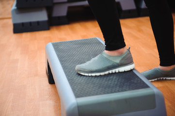 Athletic woman trainer doing aerobic class with steppers. Sport and health concept.