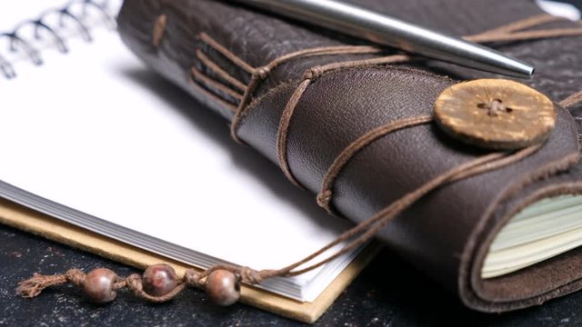 Close up on leather vintage retro notebook on a dark table. Old type diary