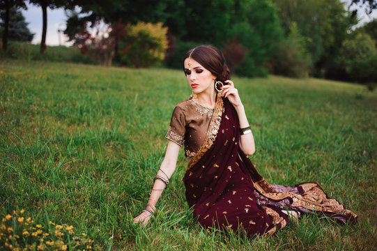 Indian girl with oriental jewellery and make-up henna applied to hand. Brunette Hindu model girl with Indian jewels.