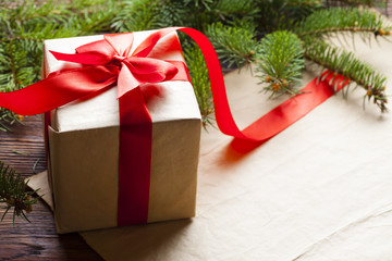 Christmas gift and spruce tree on paper and wooden background