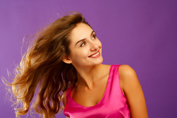 Beautiful young woman posing in studio over violet background. Fashion concept.