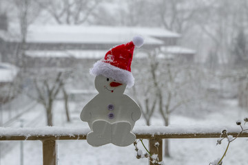 Schneemann aus Holz mit Weihnachtsmütze im Schnee