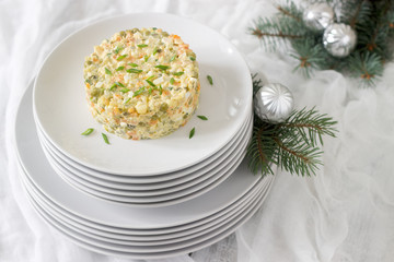 Traditional celebratory salad Olivier on a white plate with a New Year's or Christmas decor. Soviet traditions.