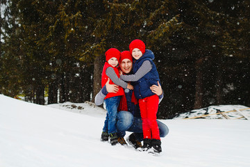Fototapeta na wymiar Father and his two sons having fun in winter in snow forest