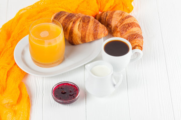 Freshly baked croissant orange juice, jam, cup of black coffee on white wooden background. French breakfast. Fresh pastries for morning. Delicious dessert. Closeup photography. Horizontal banner