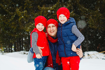 Father and his two sons having fun in winter in snow forest