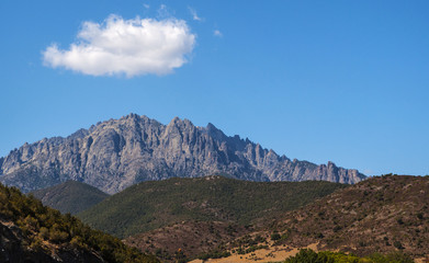 Fototapeta na wymiar Corsica, 31/08/2017: il paesaggio selvaggio dell'entroterra corso con vista del profilo del Monte Cinto (2.706 metri), la montagna più alta dell'isola e una delle vette più importanti d'Europa