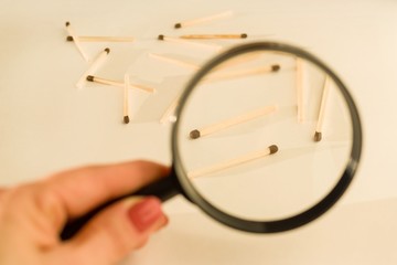 Fototapeta premium Match sticks with brown heads in a row. Matches under magnifier, white background.