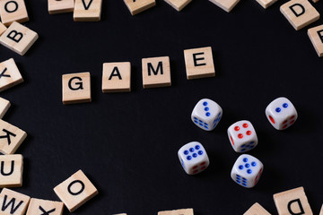 Word GAME with wooden letters on black Board with dice and letter in the circle