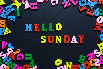 concept design - the word HELLO on SUNDAY from multi-colored wooden letters on a black background, creative idea