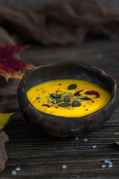 Homemade pumpkin cream soup with pumpkin seeds and pumpkin oil on a dark background. Rustic style