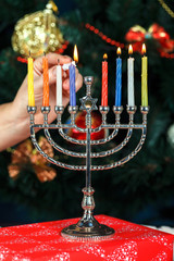Menorah with candles for Hanukkah on the background of the New Year tree © shandor_gor