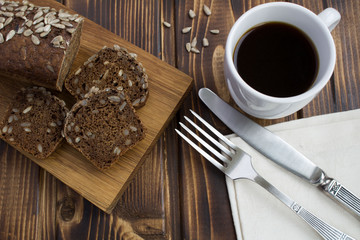 Coffee and bread with sunflower seeds on the  wooden background.View from above.