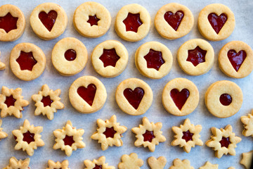 Linzer Christmas cookies filled with strawberry jam on parchment paper