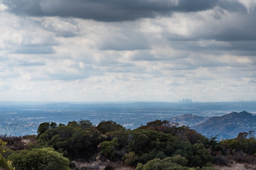 Fototapeta premium A view of the Los Angeles skyline from distant mountains with dark clouds hanging above.