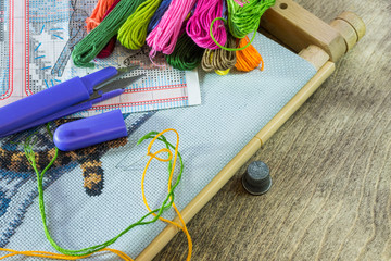 The process of cross-stitch. Canvas on hoops, needles, embroidery floss and pattern