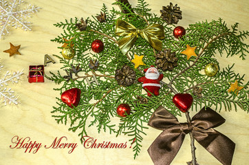 Merry Christmas with a sprig of cypress, decorated with pine cones,chocolates,hearts, satin bows and a toy Santa Claus
